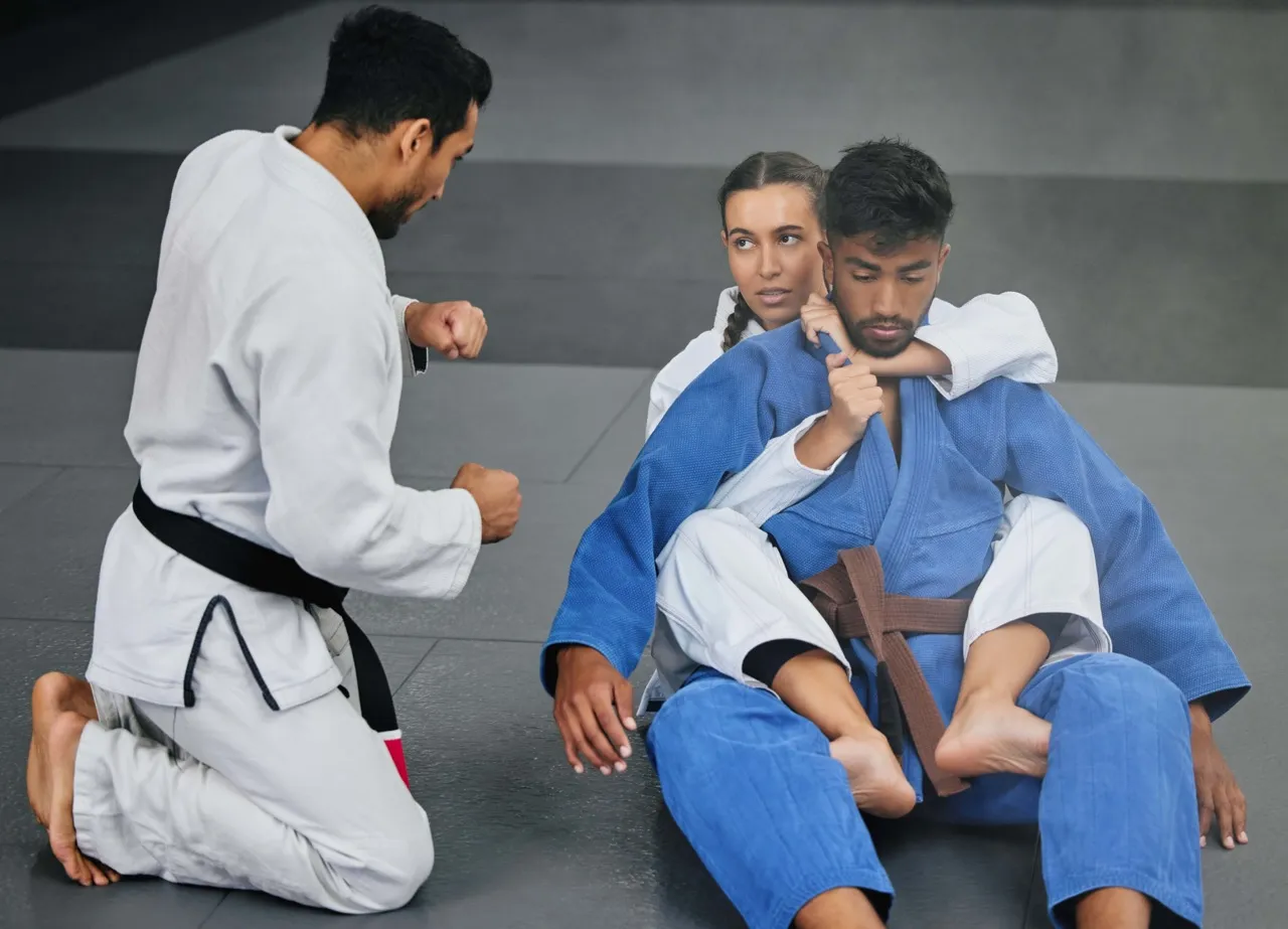 A coach and student trading collar grips during a gi round.