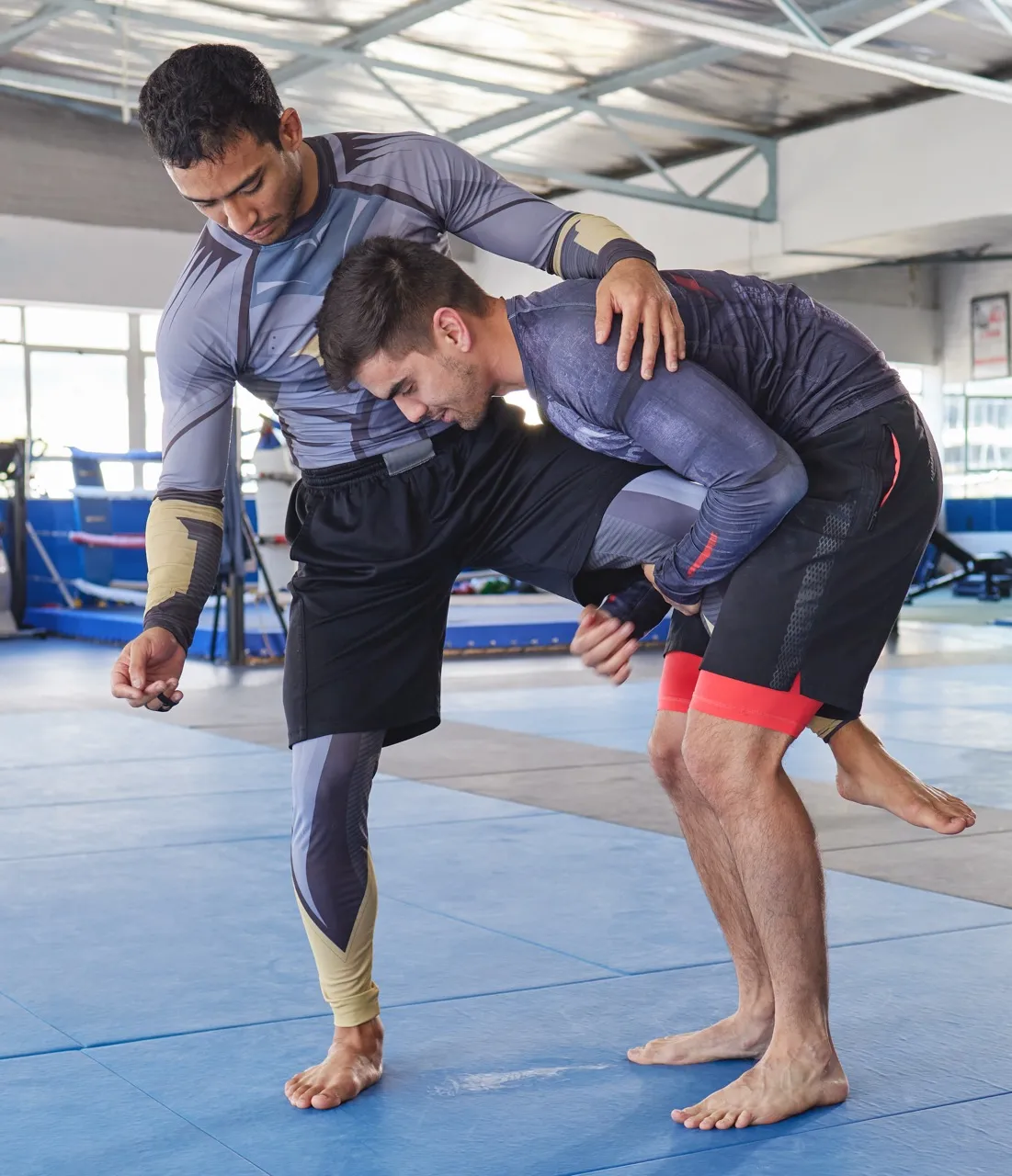 Two Atlas Grappling competitors mid no-gi single-leg takedown on the mat.